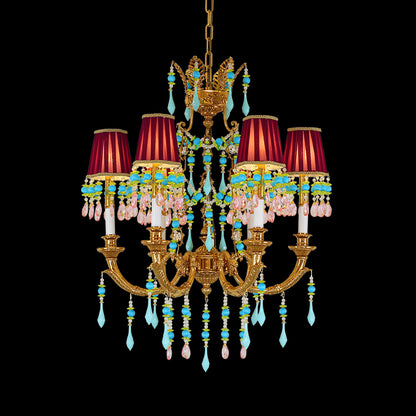 Close-up of a brass chandelier with red fabric shades and blue crystal decorations.