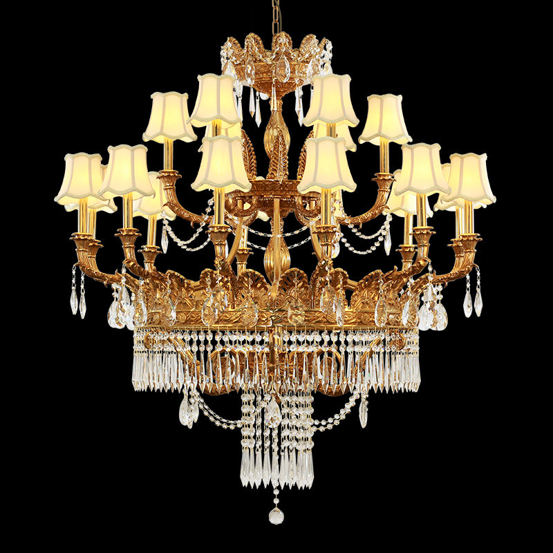 Golden brass chandelier with beige fabric shades and crystal drops isolated on black background.