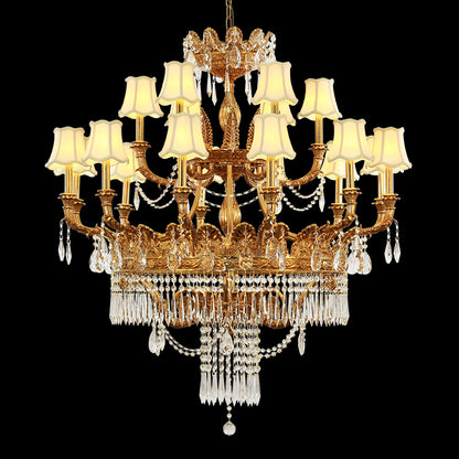 Golden brass chandelier with beige fabric shades and crystal drops isolated on black background.