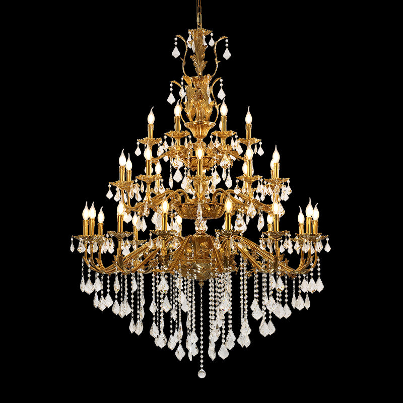 A grand foyer illuminated by the large-scale brass chandelier, featuring ornate ceiling moldings and a sweeping staircase.