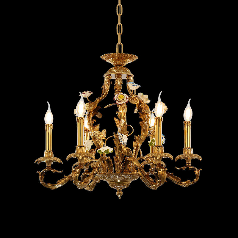 Decorative brass chandelier with bird figurine and ceramic flowers, featuring six candle bulbs.