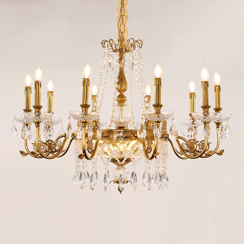 A lit, multi-tiered crystal and brass chandelier in a white room.