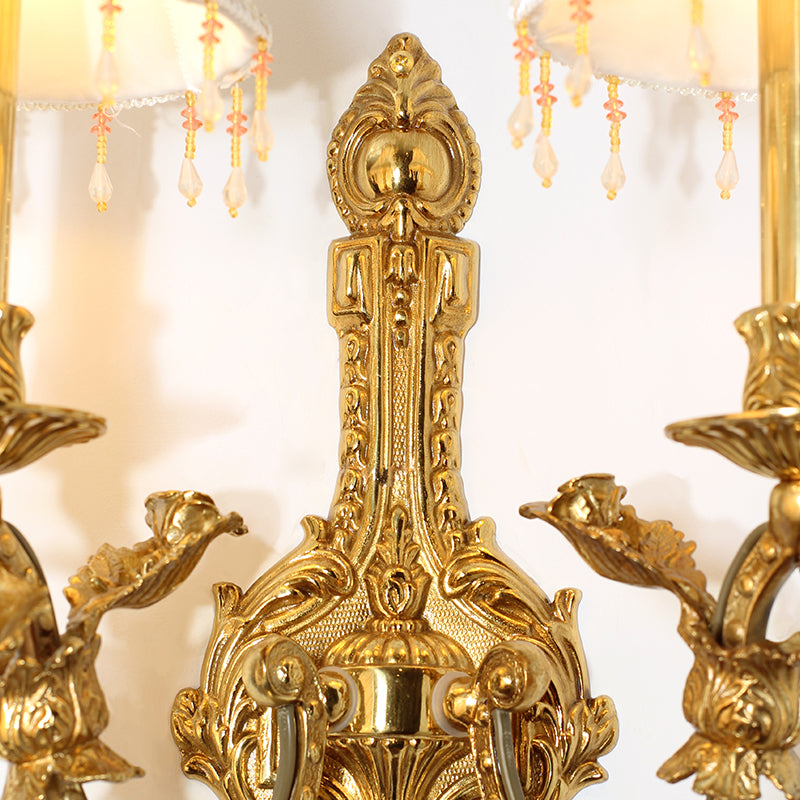 Extreme close-up macro detail of the sconce’s central brass column, featuring intricate floral and bird (bird-shaped) carvings.