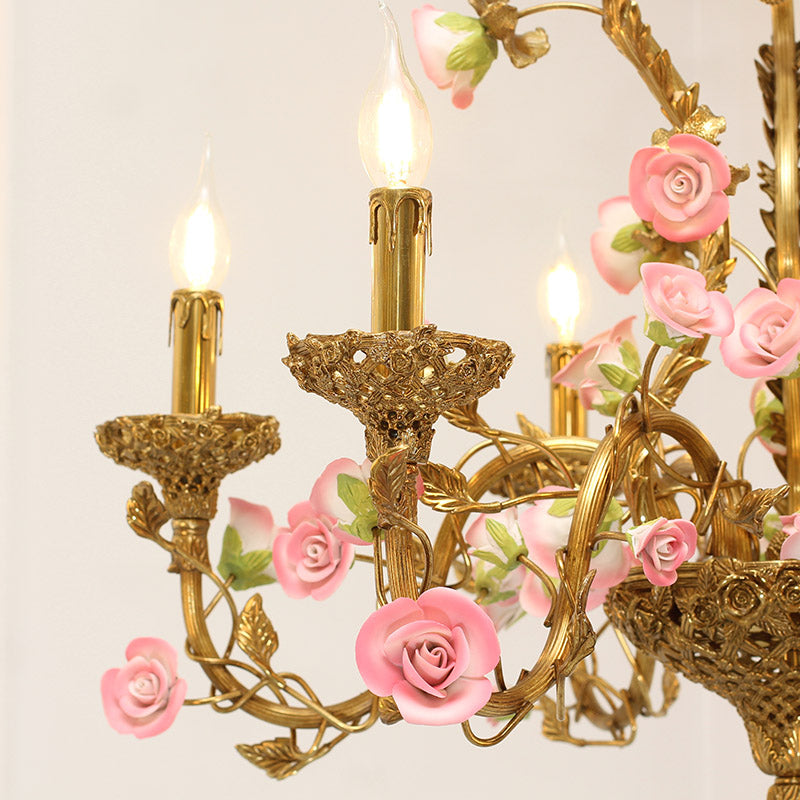 Macro close-up of the finely detailed golden brass leaves and a single hand-painted pink rosebud.