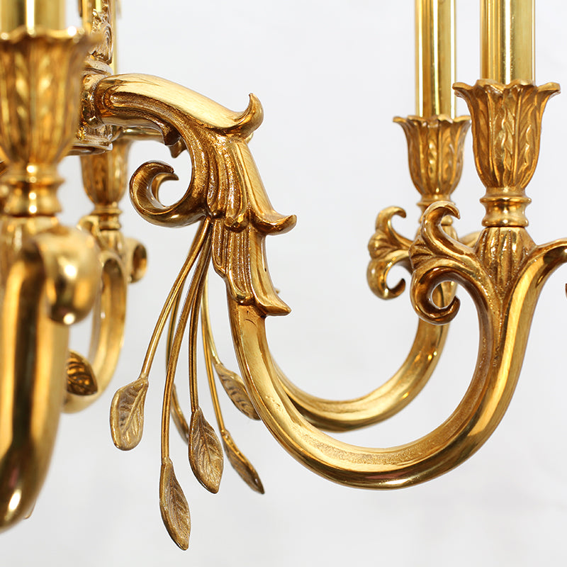 Macro detail of a curved brass arm with intricate scrollwork and classical motifs.