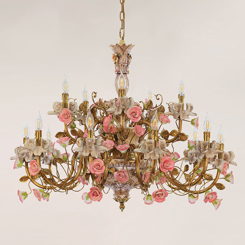 Multi-arm brass chandelier with ceramic floral decorations, displayed on a light wall.