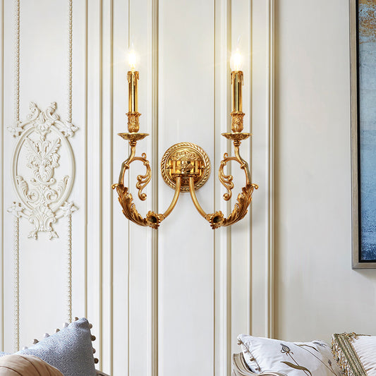 The golden traditional wall sconce installed on a light-colored wall with decorative white molding and blue artwork.