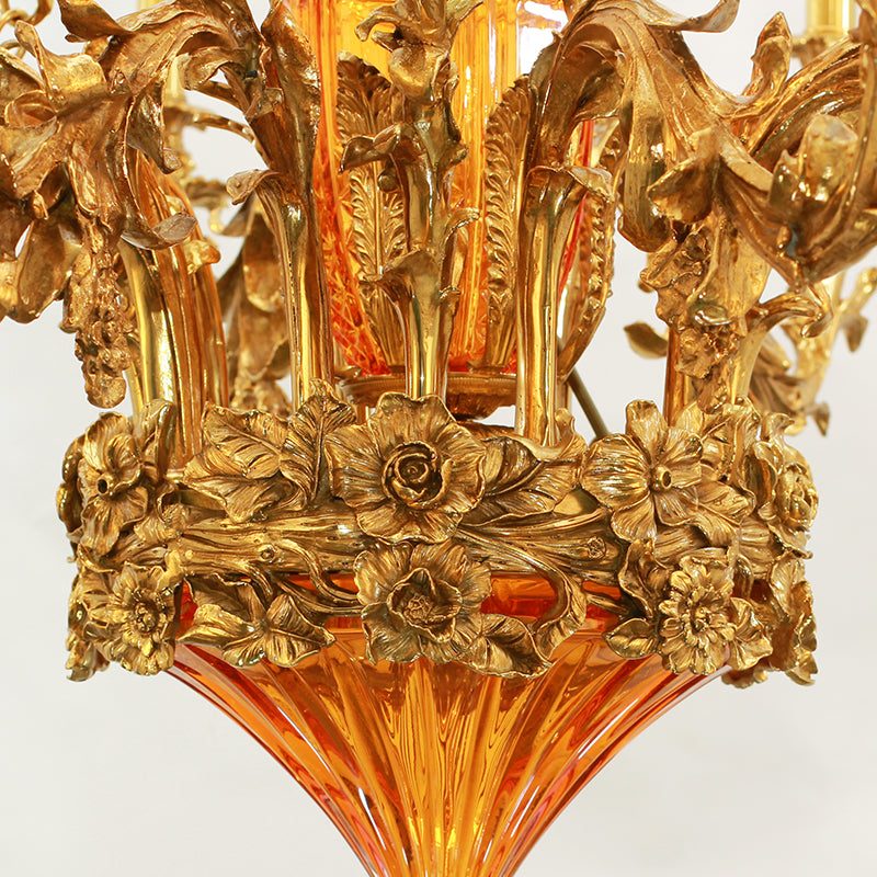 Extreme close-up of detailed brass pomegranate and leaf on the chandelier's central column.