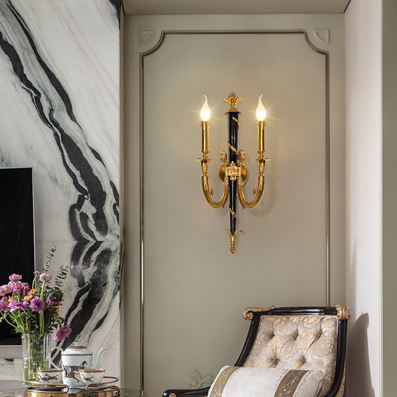 The luxury antique bronze wall light installed in an elegant interior with a vase of pink peonies and a gold chair.