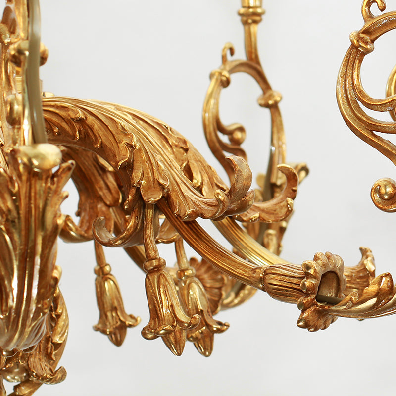 Macro detail of intricate scrollwork and decorative elements on a classical brass chandelier arm.