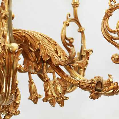 Macro detail of intricate scrollwork and decorative elements on a classical brass chandelier arm.