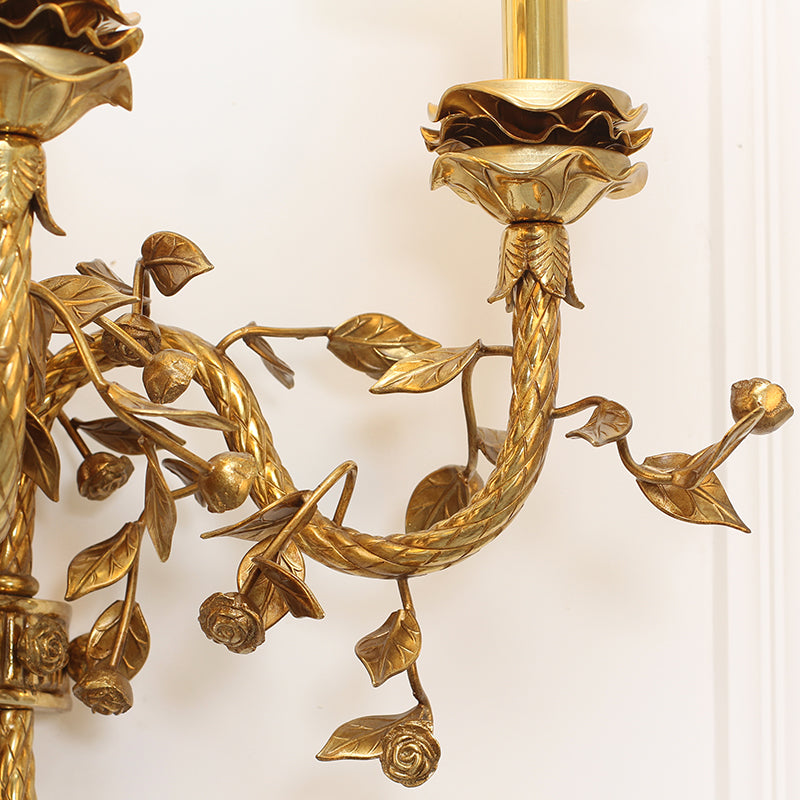 Macro detail of a single curved arm, highlighting the hand-carved grape clusters and textured leaves on the wall lamp.