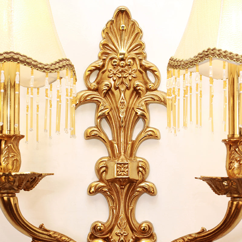 Close-up macro detail of the sconce’s ornate central brass column, showcasing intricate floral and leaf carvings.