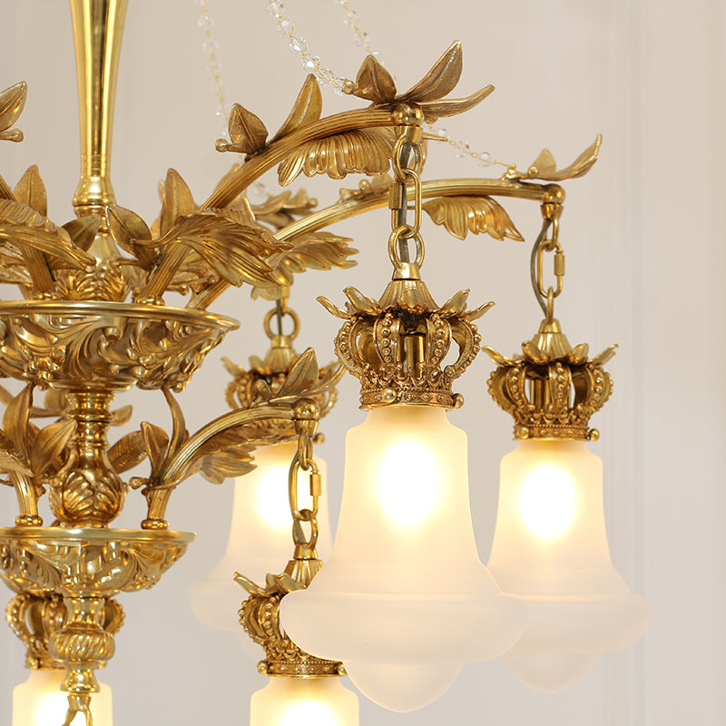 Detailed view of the chandelier's crown-shaped top, brass arms, and white glass lampshades.
