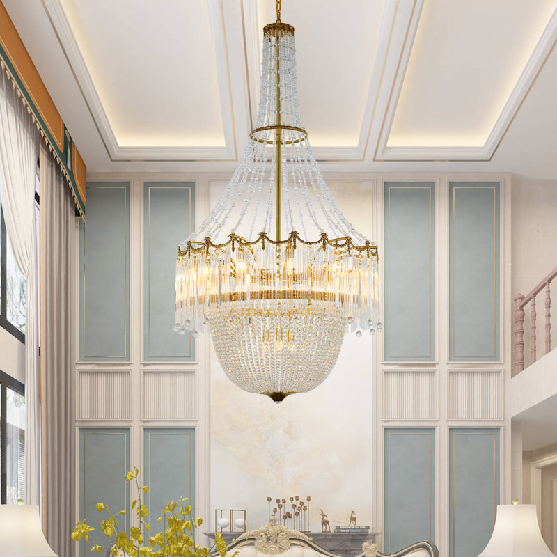 A luxury chandelier installed in a grand hotel lobby with high ceilings, coffered panels, and elegant wall sconces.