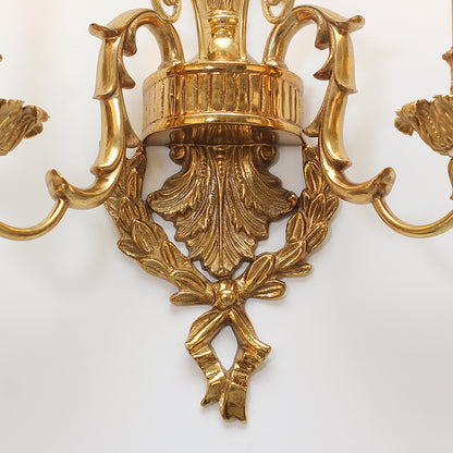 Macro detail of the intricately crafted ribbon bow and leaf patterns on the brass surface.