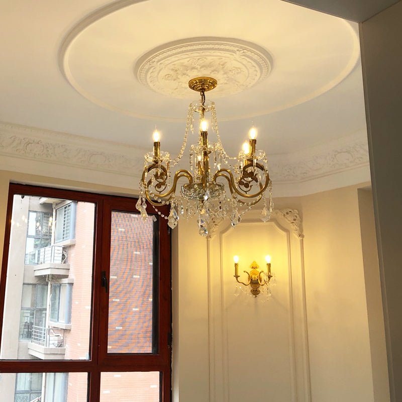 The crystal brass chandelier installed in a living room with a cove ceiling and matching sconce.