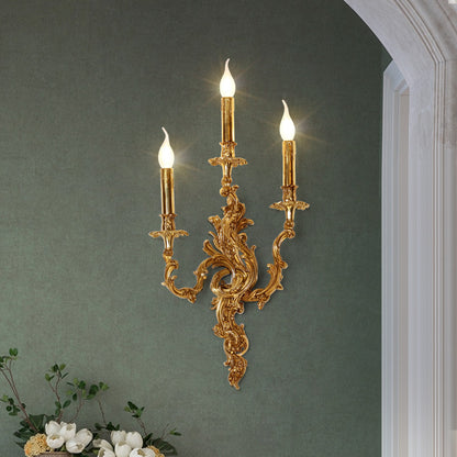The three-light French classical wall lamp installed on a sage green wall with white trim and floral decor.