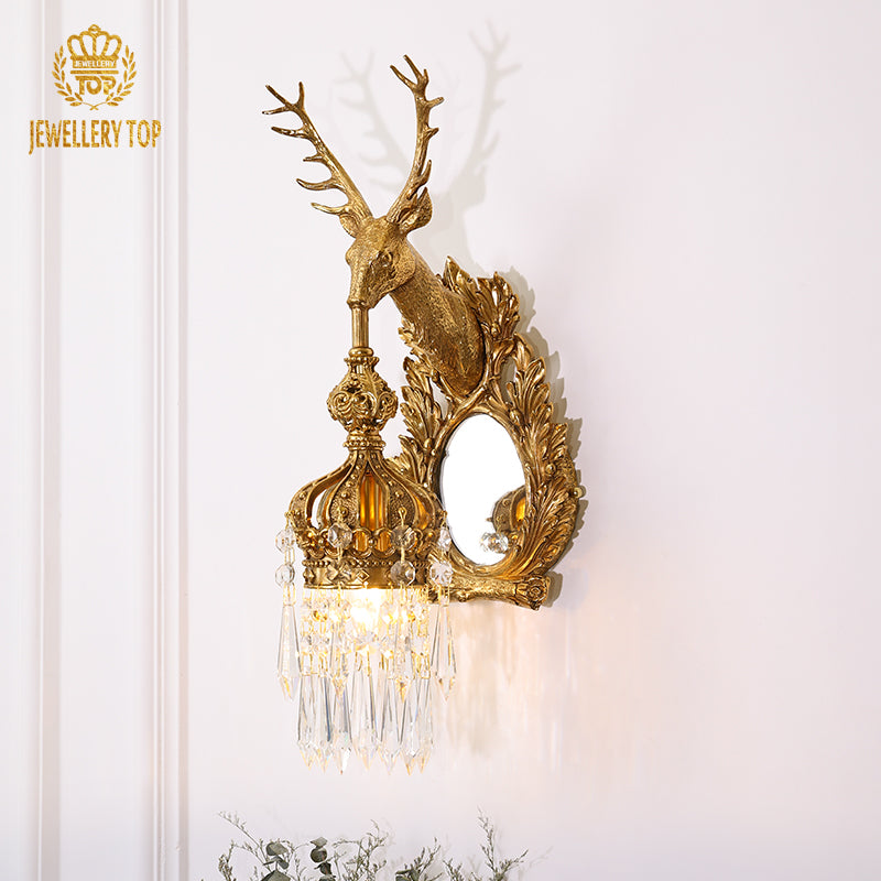 Front view of the ornate brass wall lamp highlighting the stag sculpture, mirror, and crystal details.