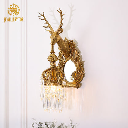 Front view of the ornate brass wall lamp highlighting the stag sculpture, mirror, and crystal details.