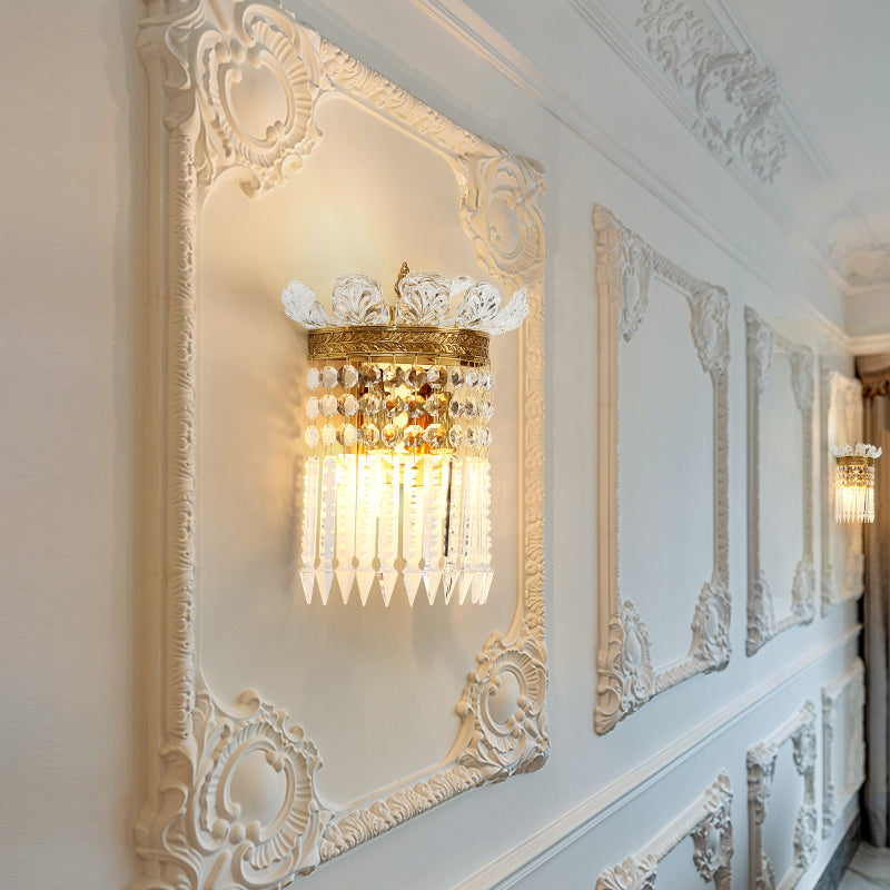 The luxury crystal wall lamp installed on a light-colored wall with wainscoting, emitting a warm, sparkling glow.