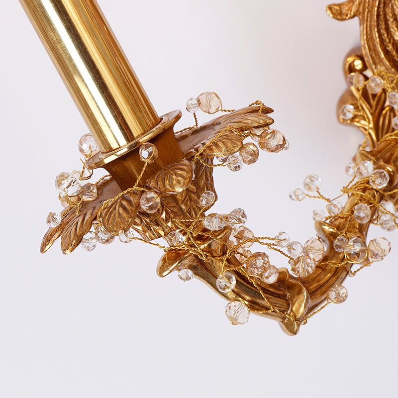 Detailed close-up of a brass arm adorned with strings of clear crystal beads on the high quality wall light.