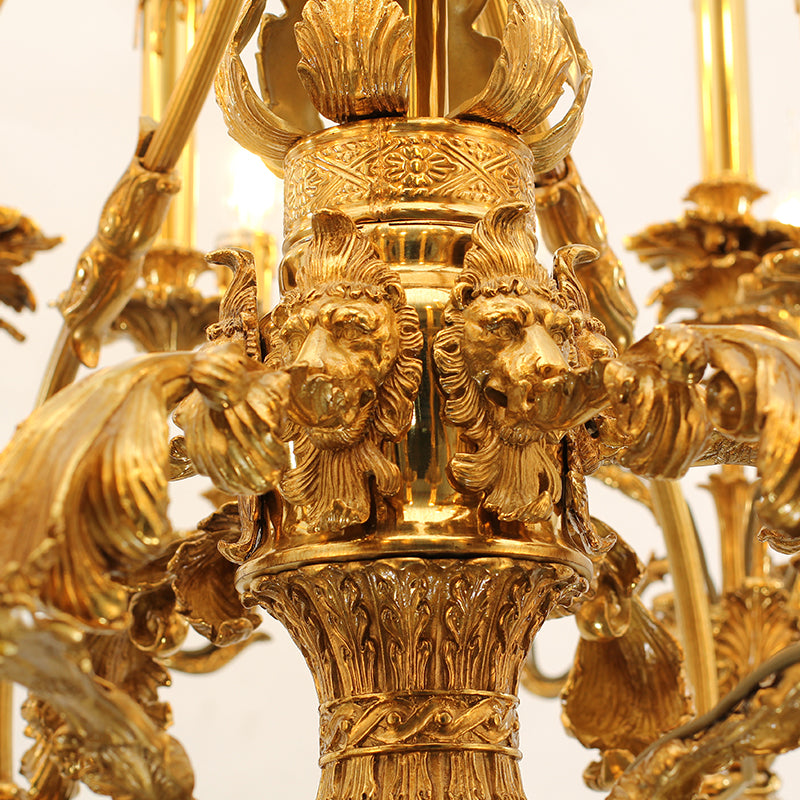 Extreme close-up of majestic lion head carvings on the central column of a luxury brass chandelier.