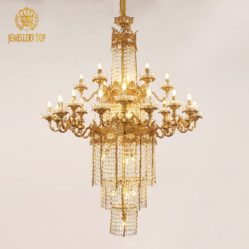 JEWELLERY TOP brand's ornate large brass chandelier with dense crystal fringe against a wall.