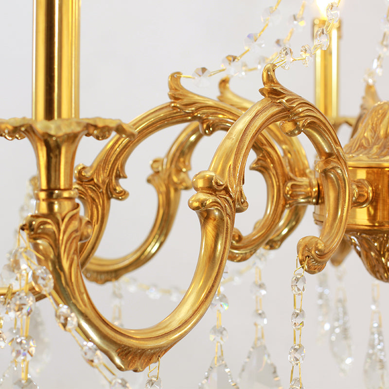 Macro close-up of ornate Baroque brass scrollwork, a candle cup, and crystal chains.