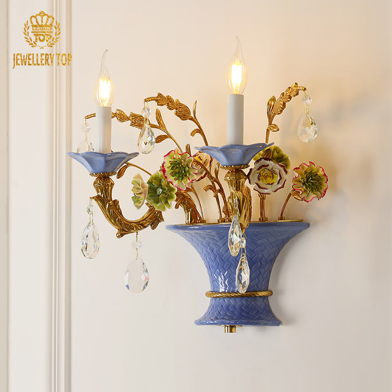 JEWELLERY TOP brand close-up of the sconce, showcasing the blue ceramic base and detailed brasswork on white.