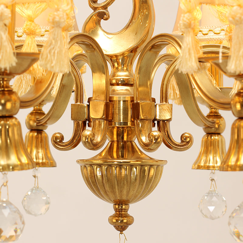 Macro shot of a fabric lampshade with tassel trim and the chandelier's ornate brass centerpiece.