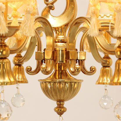 Macro shot of a fabric lampshade with tassel trim and the chandelier's ornate brass centerpiece.