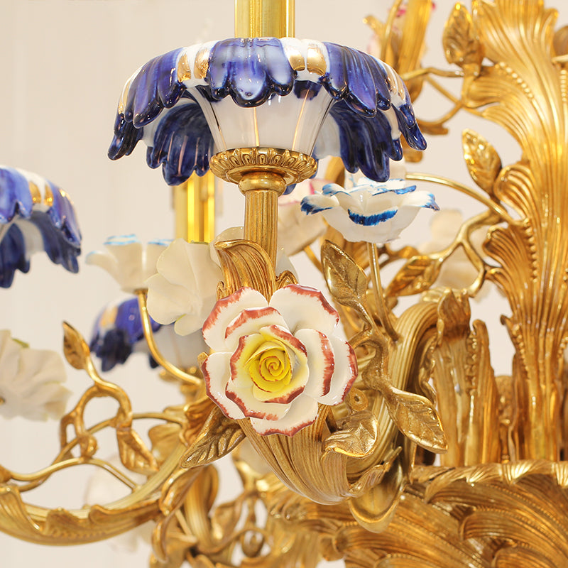 Extreme close-up of a red and white ceramic rose and blue floral details on the brass chandelier.