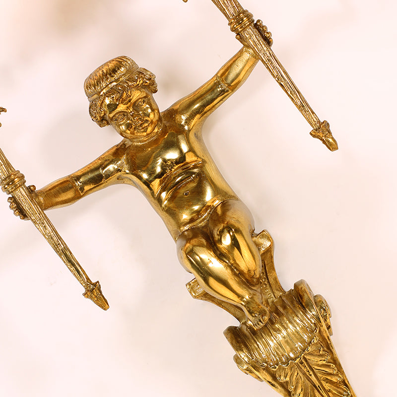 Detailed macro shot focusing on the winged cherub sculpture, capturing the textured wings and playful posture of the brass figure.