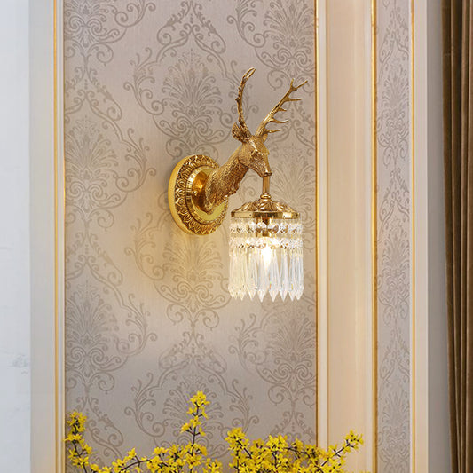 The European brass wall sconce with a lit bulb, installed on a light-colored wall, showcasing its warm glow and crystal details.