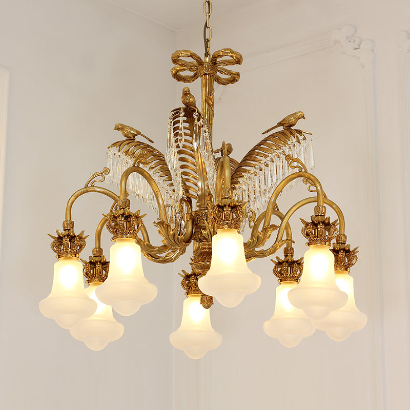 Close-up detail of the ornate brass palm frond and hanging crystal droplets on the chandelier.