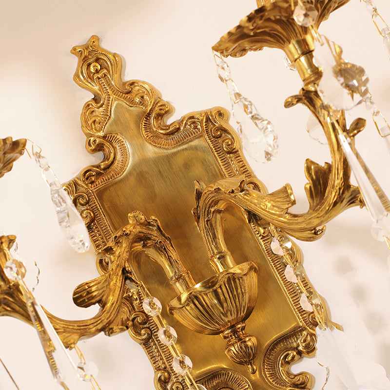 Extreme close-up of the sconce’s central backplate, showing the precise Rococo-style engravings and aged brass patina.