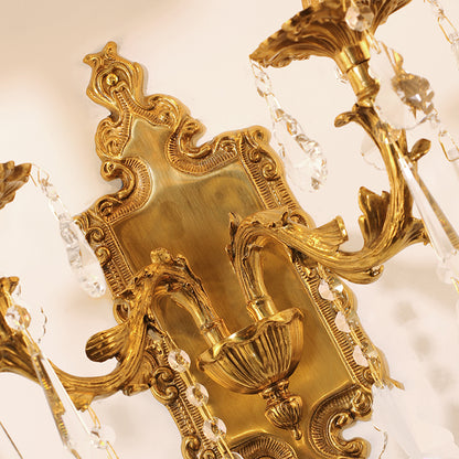 Extreme close-up of the sconce’s central backplate, showing the precise Rococo-style engravings and aged brass patina.