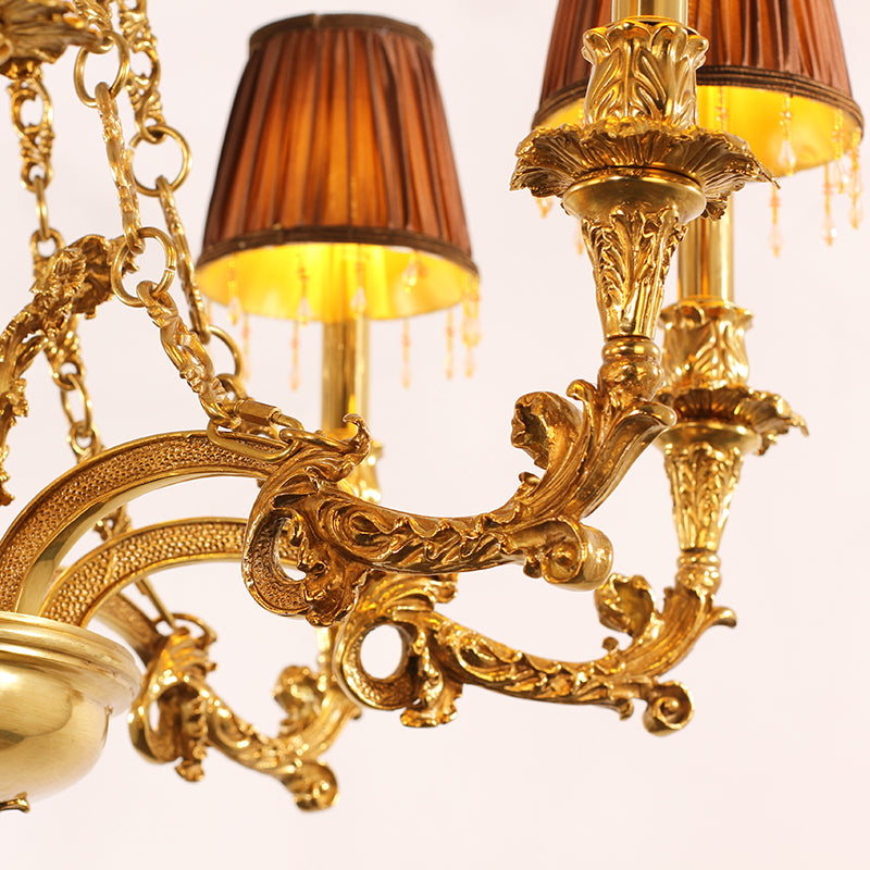 Close-up detail of ornate brass scrollwork and a fabric lampshade on a luxury chandelier.
