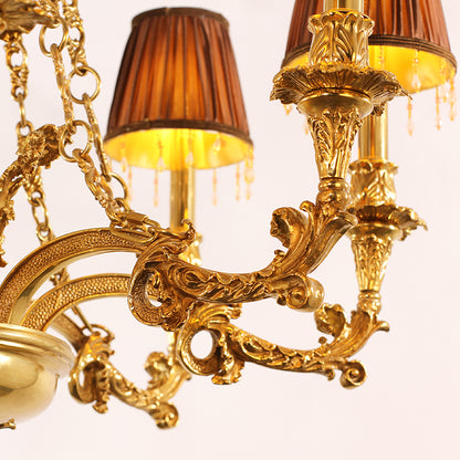 Close-up detail of ornate brass scrollwork and a fabric lampshade on a luxury chandelier.