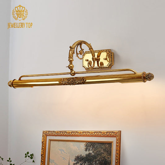 The vintage brass wall lamp installed above a bathroom mirror, reflecting in the glass alongside decorative bottles.