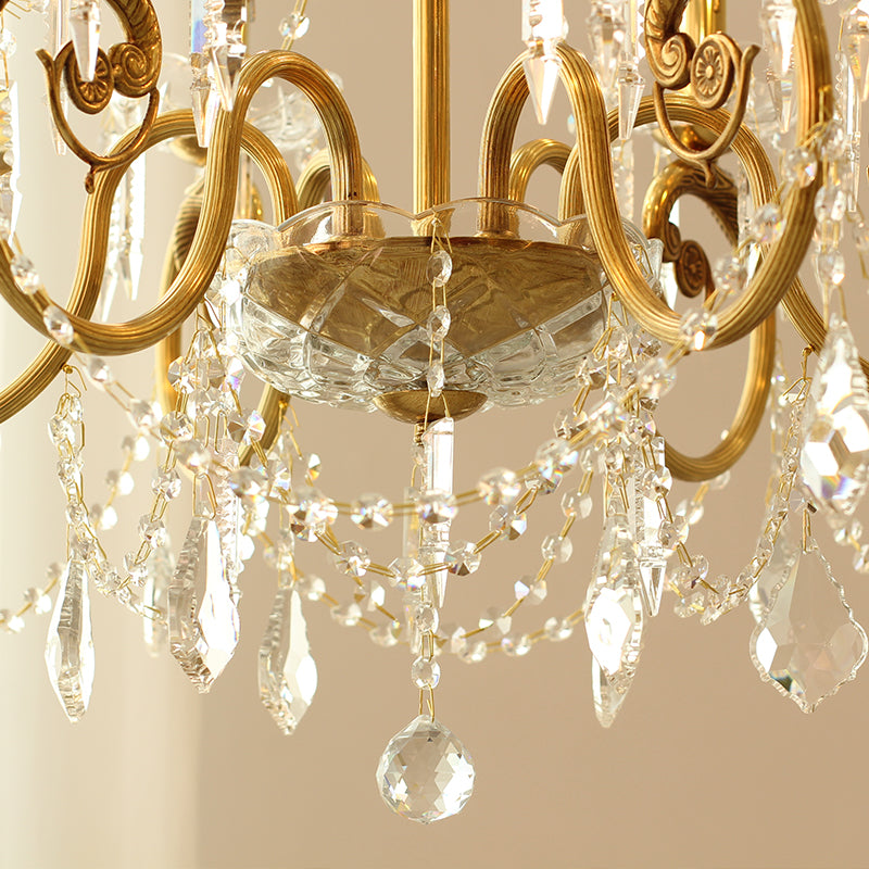 Extreme close-up detail of ornate brass scrollwork and layered crystal strings on the chandelier.
