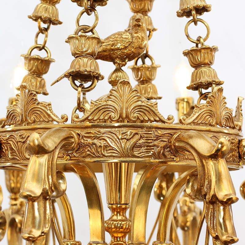 Extreme close-up of the detailed brass bird perched on an urn, with ornate leaf carvings.