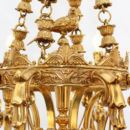 Extreme close-up of the detailed brass bird perched on an urn, with ornate leaf carvings.