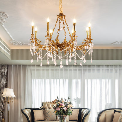 Antique brass chandelier installed in a living room with sofa, pillows, and flowers by a window.