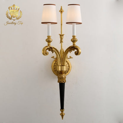 View the elegant symmetry of The Athena Victorian wall sconce by Jewellery Top. Featuring solid brass, fabric shades, and a striking 35-inch height.