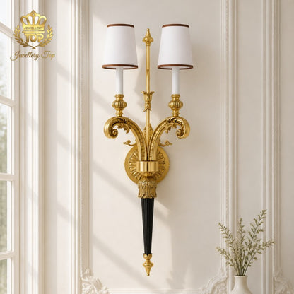 Brighten your classic interior with The Athena wall sconce by Jewellery Top. Solid brass and white fabric shades create timeless elegance in any room.